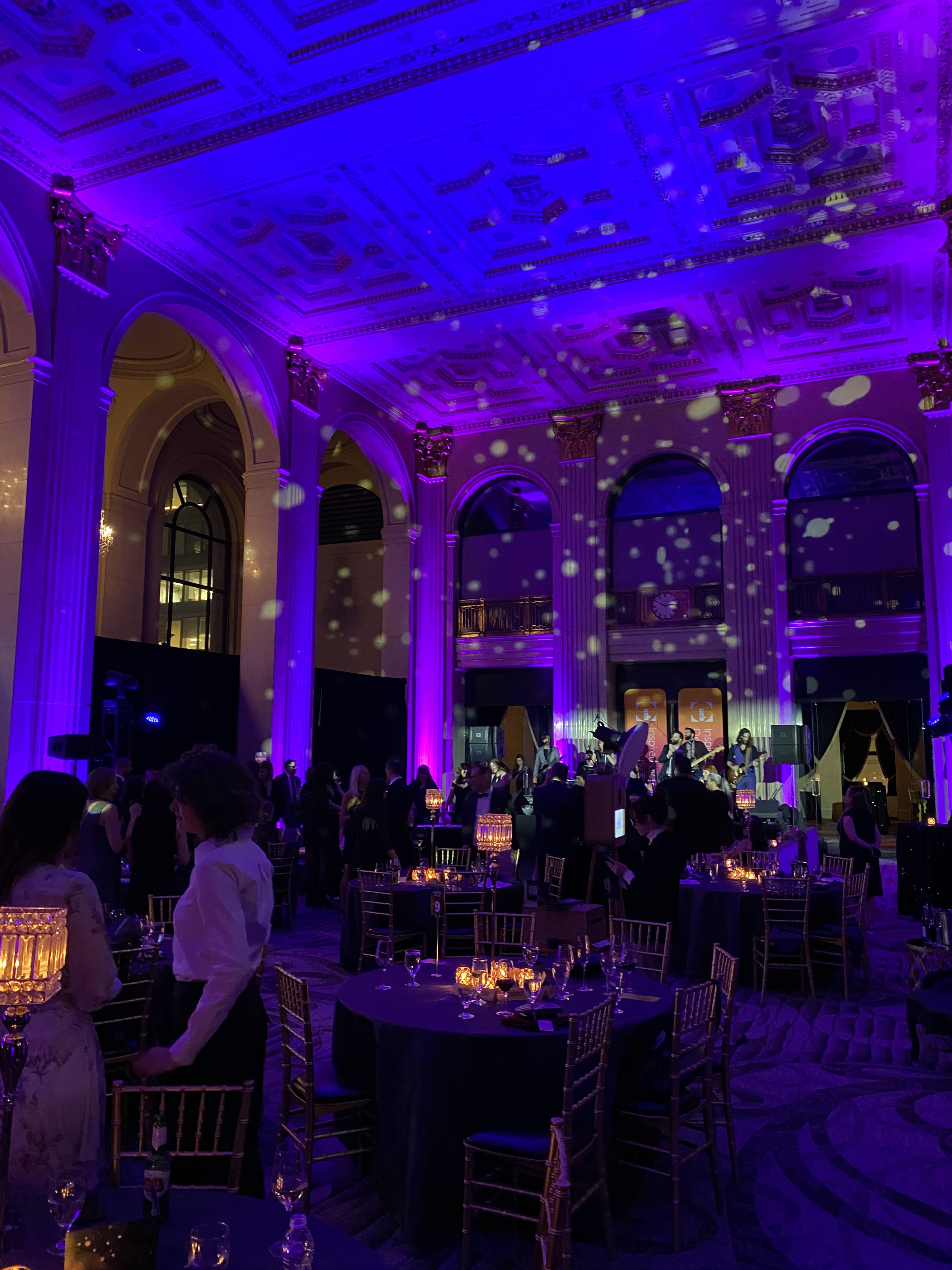 Purple-lit gala dinner with bokeh ceiling lights