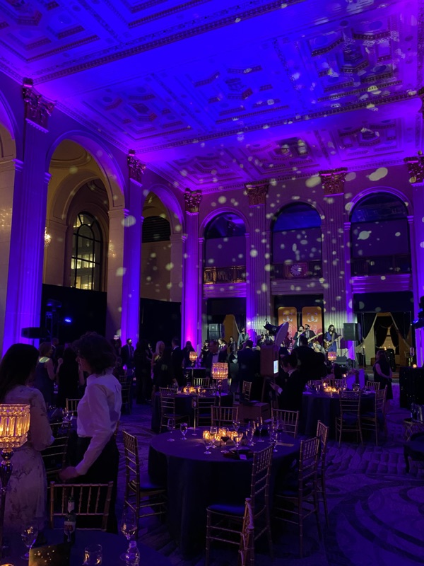 Purple-lit gala dinner with bokeh ceiling lights